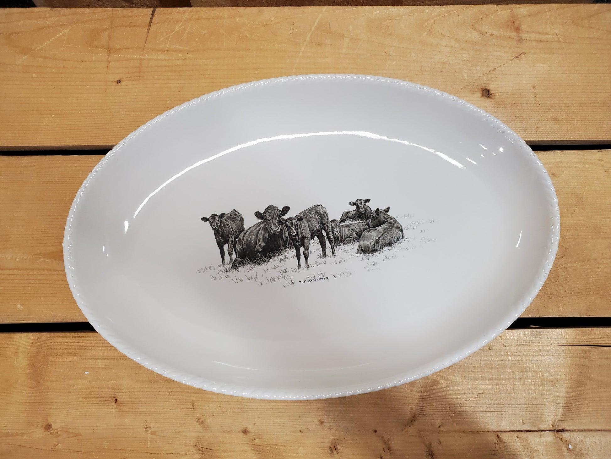 A white serving platter with a printed illustration featuring resting cows