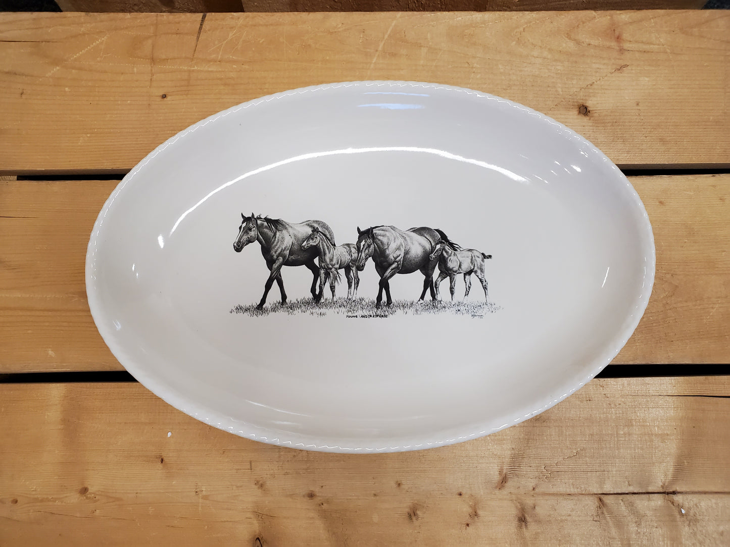 A white serving platter with a printed illustration featuring two mares and two foals