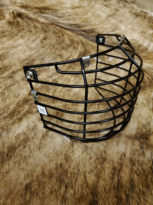 A black crooked horn helmet cage placed on a textured surface, presumably a part of bull riding gear.