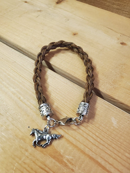 a braided horsehair bracelet with a horse charm on a wooden background