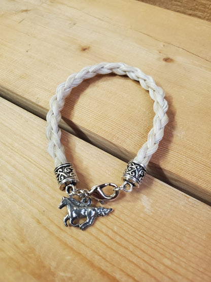 a braided horsehair bracelet with a horse charm on a wooden background
