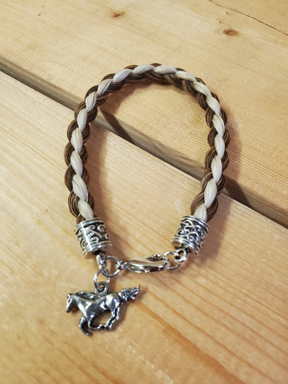 a braided horsehair bracelet with a horse charm on a wooden background