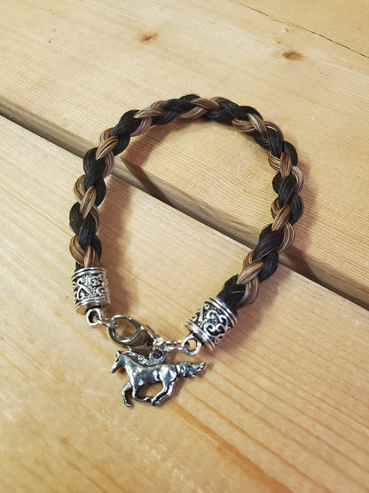 a braided horsehair bracelet with a horse charm on a wooden background