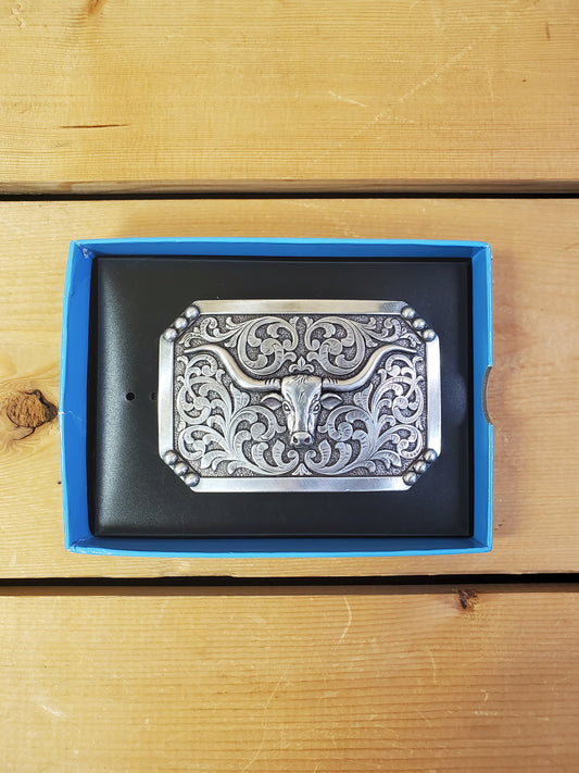 A Nocona brand smooth edge long horn belt buckle displayed in its packaging, featuring an engraved metal belt buckle with floral patterns.