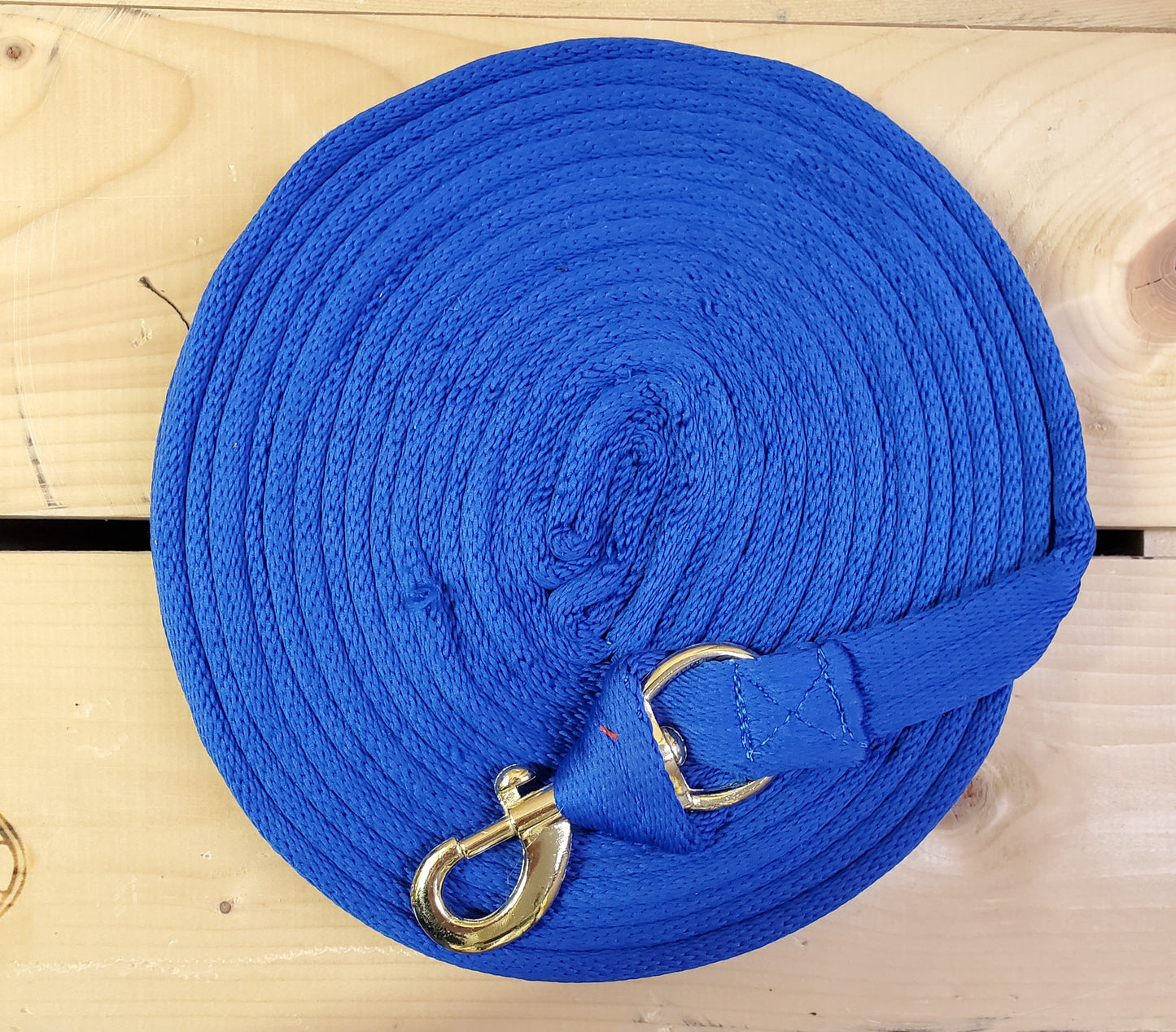 blue coiled up rope with a brass snap on a wooden background