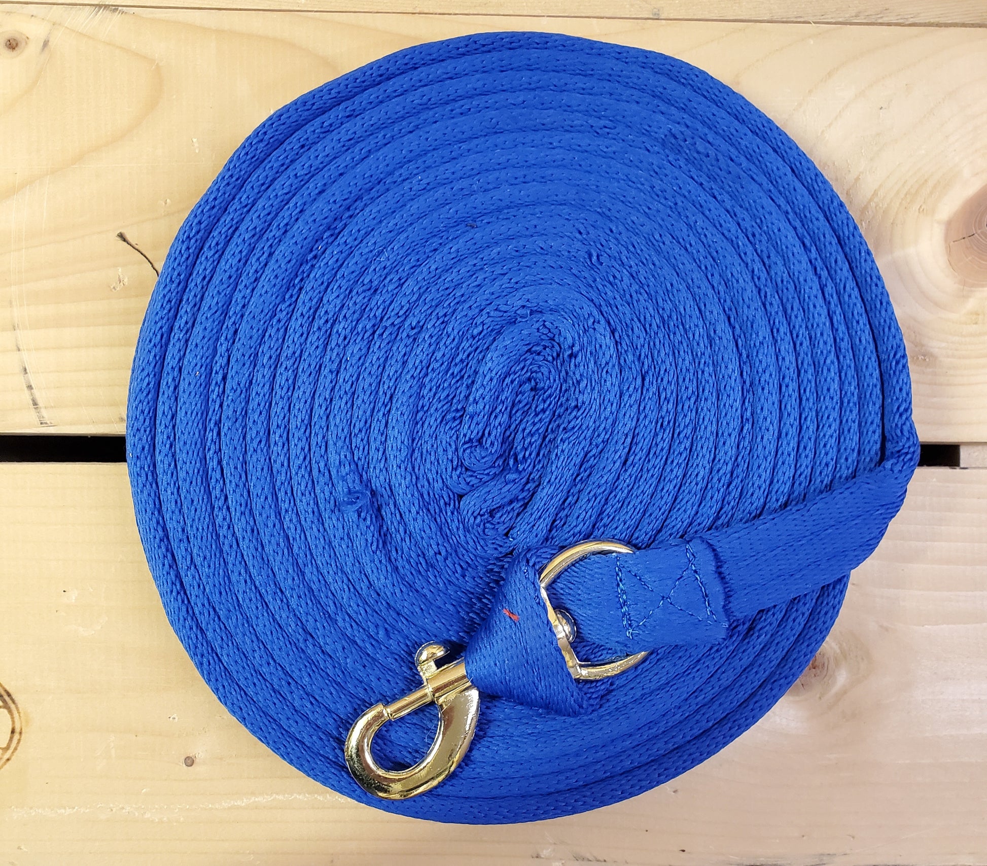 blue coiled up rope with a brass snap on a wooden background