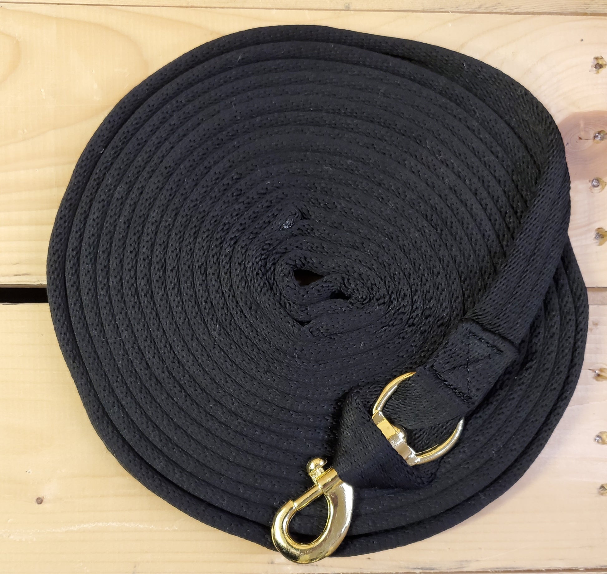 black coiled up rope with a brass snap on a wooden background