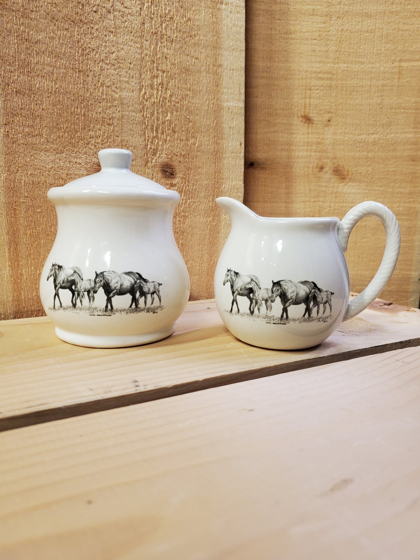 a white ceramic cream and sugar set with a black and white picture of two mares and two foals
