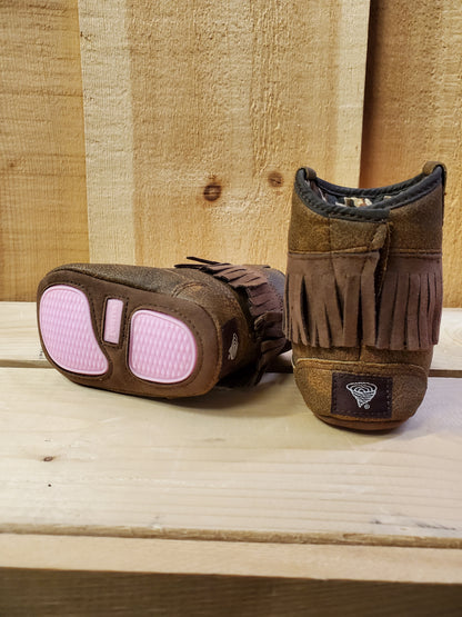 Brown baby cowboy boots with fringe on a wooden background