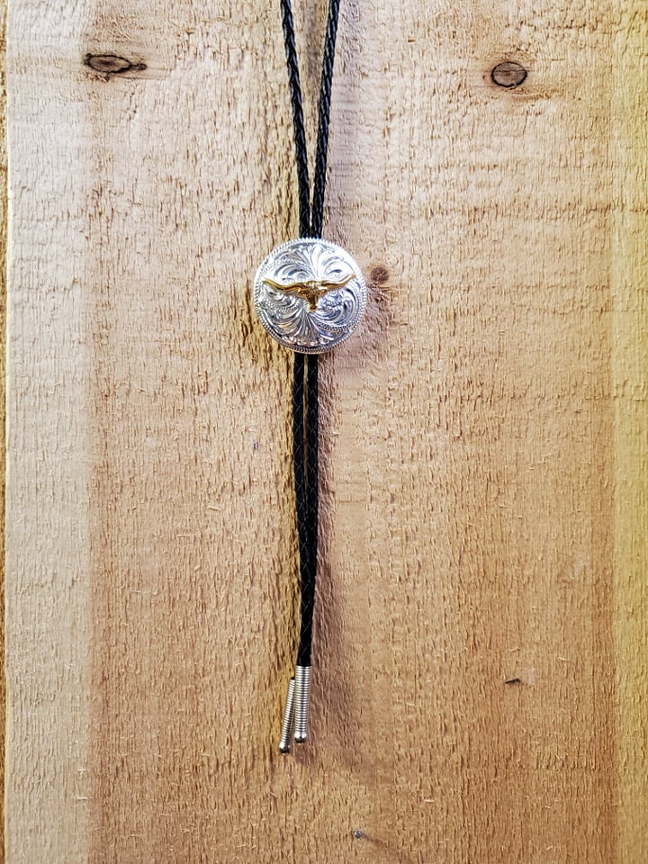 A bolo tie with a silver-colored longhorn pendant on a wooden background.