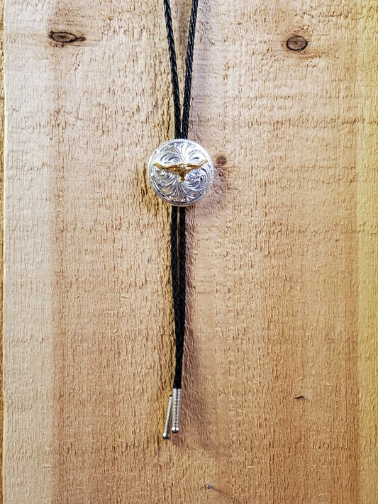 A bolo tie with a silver-colored longhorn pendant on a wooden background.