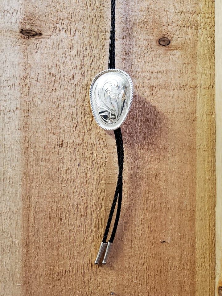 a silver bolo tie with black ties on a wooden background