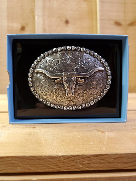 A steer head buckle with berry edge design, displayed in packaging on a wooden background
