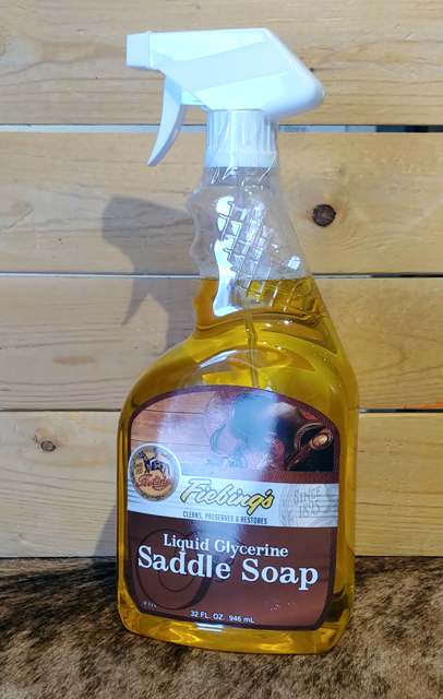 A bottle of Fiebing's Liquid Glycerine Saddle Soap with a spray nozzle on a wooden surface.