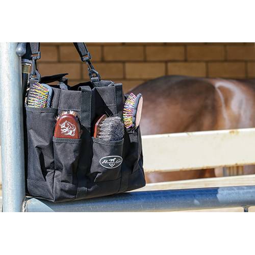 a black grooming bag with brushes in an outdoor setting with a horse in the background