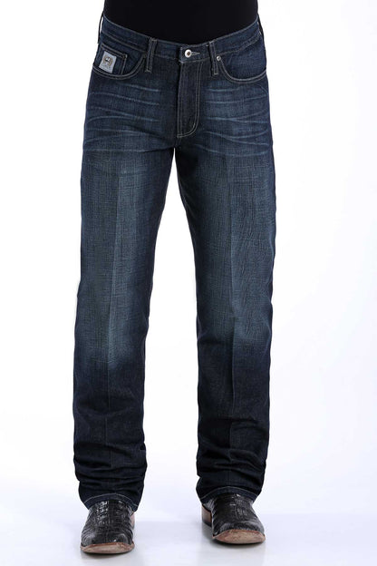 A pair of men's dark rinse denim jeans by Cinch with a slim seat and thigh, straight leg with a boot cut opening, mid-rise waist, and a small logo on the pocket.
