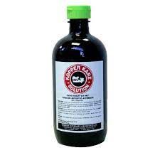 a brown bottle of kopper kare with a white label and green cap on a white background