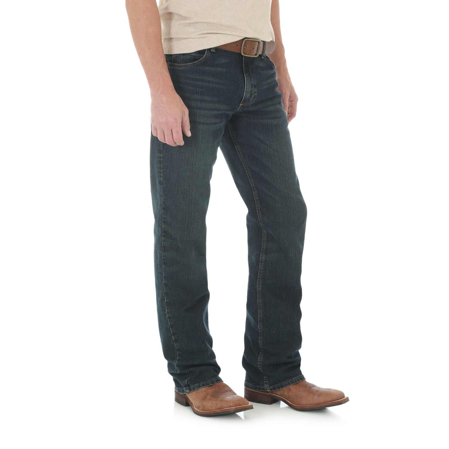 a man wearing a darkwash bootcut Wrangler jean and a tan shirt on a white background